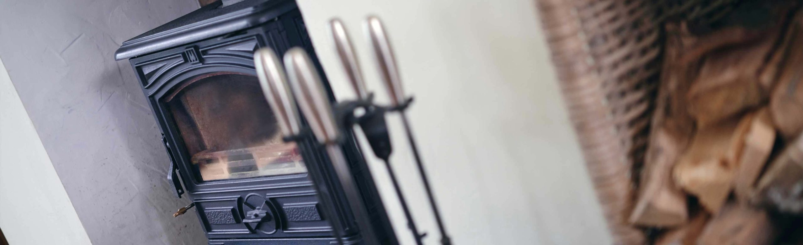 Stove fire in main focus, out of focus chopped wood to the right